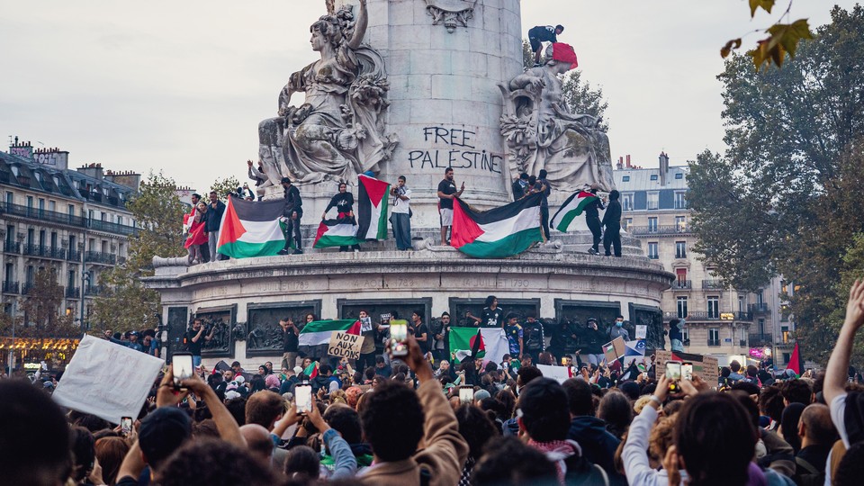 A pro-Palestinian protest including flags and signs encircles the statue at the center of Place de la Republique, in Paris.