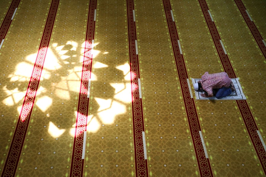 A man prays inside a large space inside a mosque.