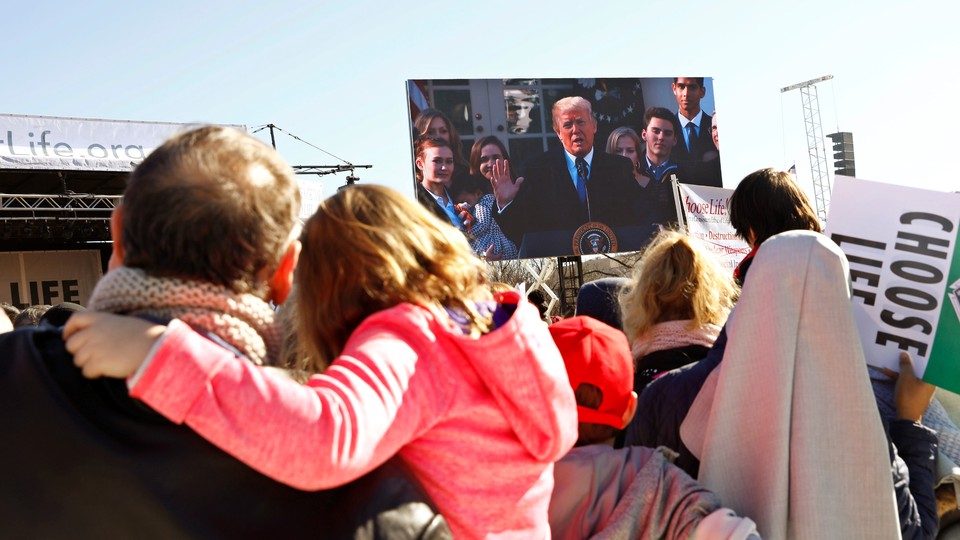 Participants watch as President Trump speaks by satellite from the White House to attendees of the March for Life rally in Washington.