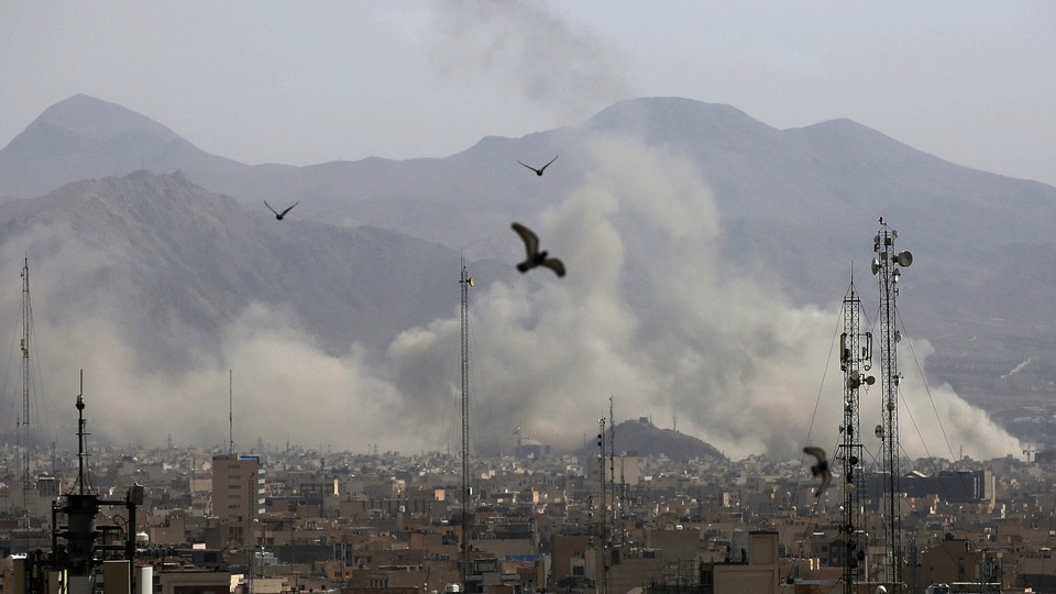 Birds fly over Tehran, with clouds of smoke visible in the background