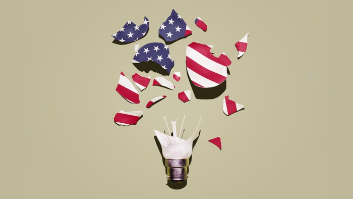 A photo illustration of a shattered lightbulb, but the glass is made up of segments of the American flag.