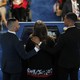 A view from behind of Christine Leinonen speaking at a podium, with Juan Arriagada and Brandon Wolf holding her shoulders