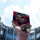 A demonstrator wearing a sun hat holds up a painting of Kilmar Abrego Garcia.