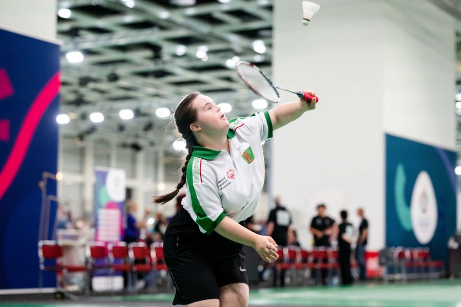 An athlete moves to hit a shuttlecock with their racquet.