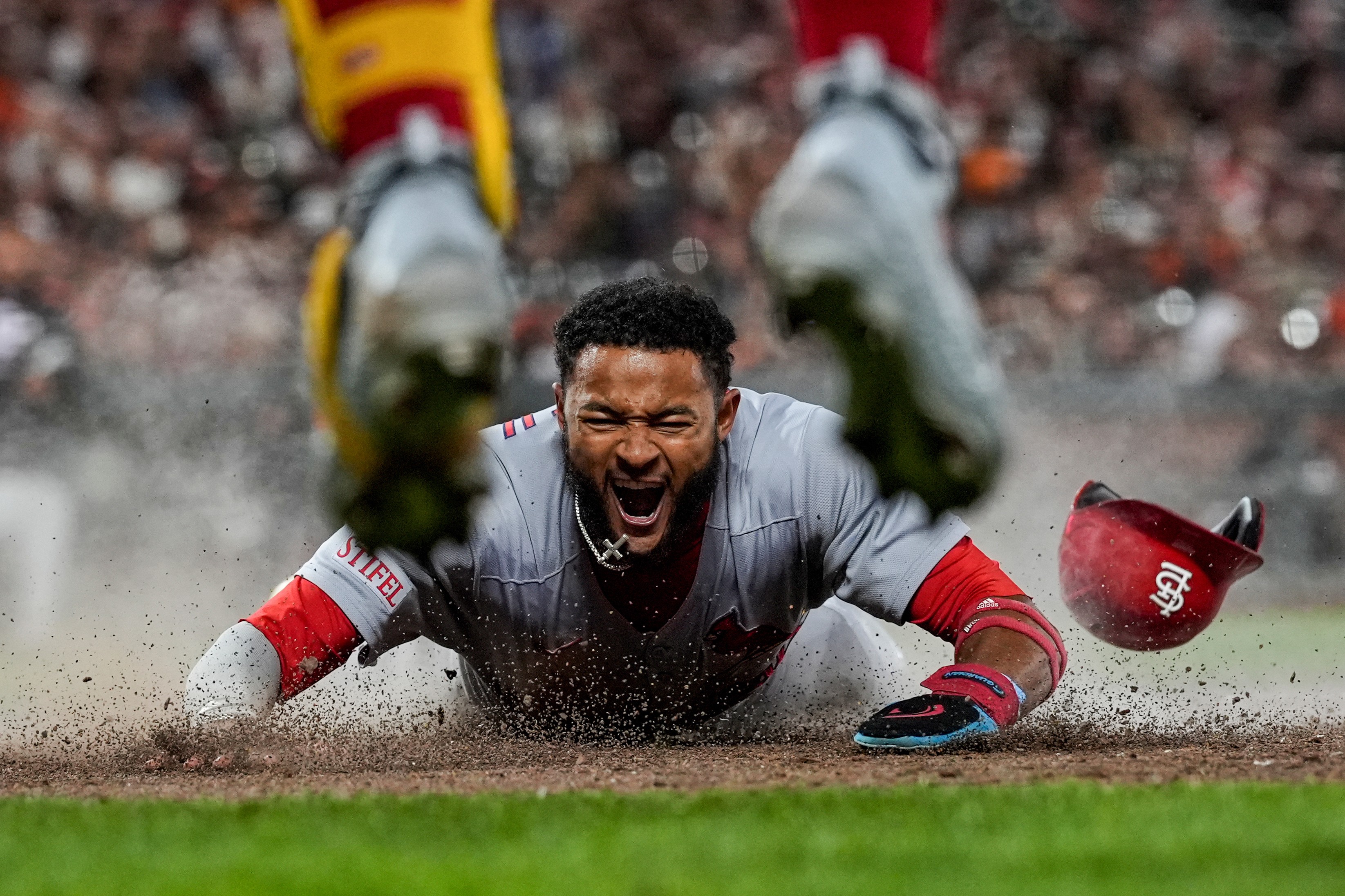 A baseball player reacts as they slide onto a base during a game.