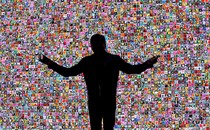A photo of Jensen Huang in silhouette in front of a mosaic of small photos of flowers, delivering a keynote address at CES in 2018