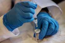 A syringe pulling a vaccine from a vial