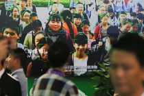 Visitors walk past a screen showing a demonstration of facial-recognition software at the Security China 2018 exhibition on public safety and security in Beijing.