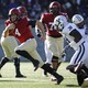 A Harvard player runs with the football away from the Yale defense