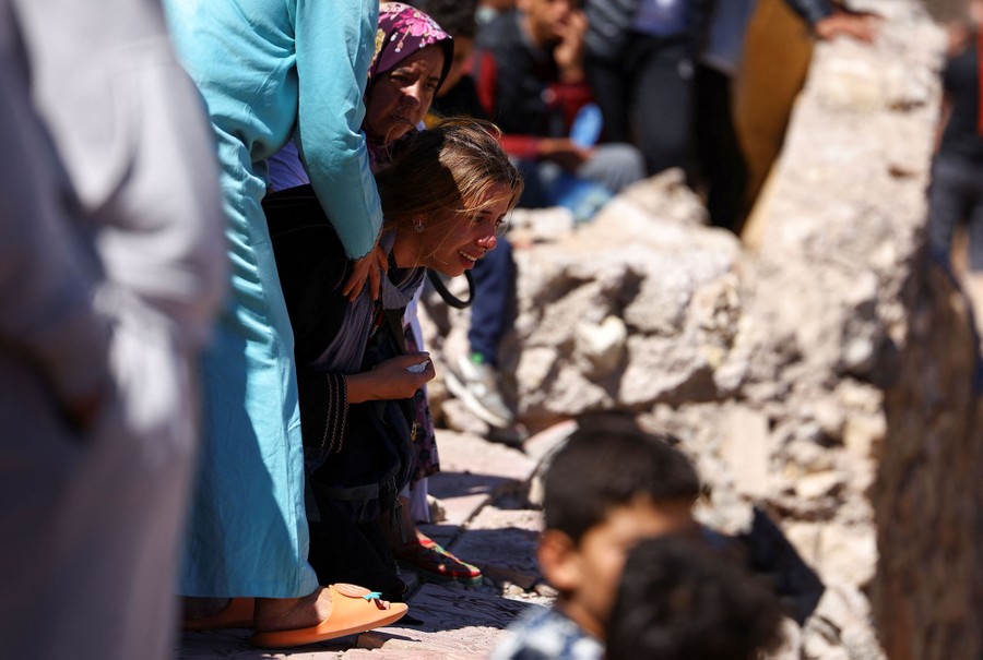 A young woman is comforted by others as she reacts during a funeral.