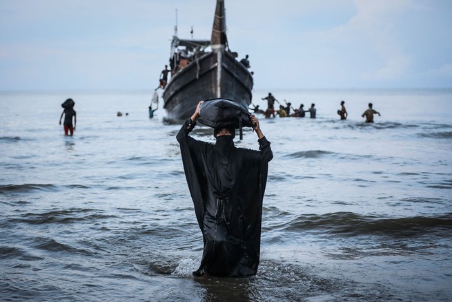 A Rohingya woman walks to the beach after the local community temporarily allowed a boat of refugees to land for water and food, in Ulee Madon, Indonesia.