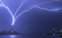 Lightning bolts arc across a dark sky as they strike One World Trade Center in New York City.