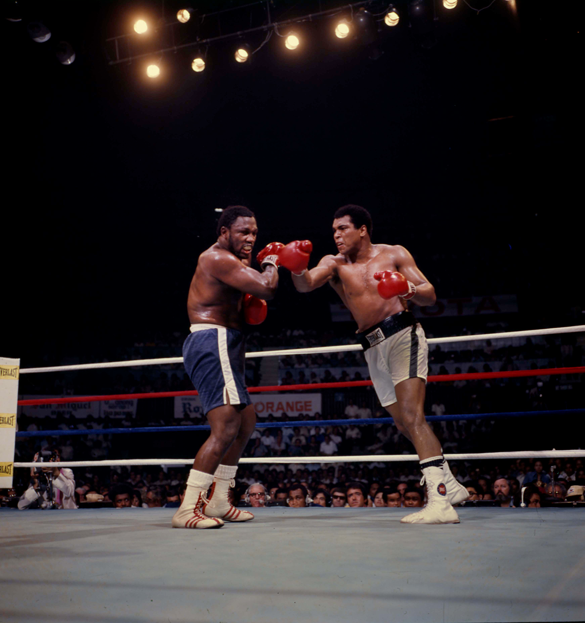 color photo of Ali and Frazier boxing, with tired Ali jabbing Frazier in center of ring