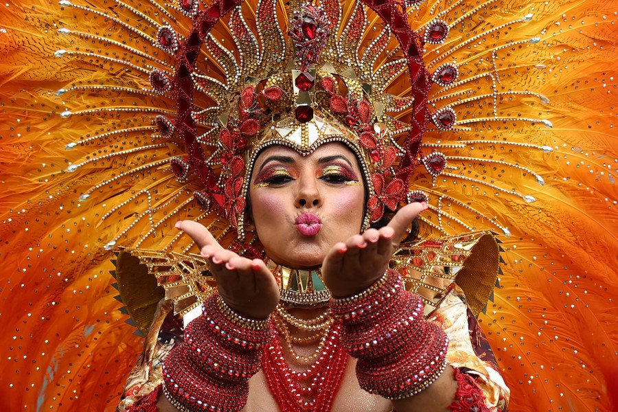 A performer in a large feathered costume blows a kiss.