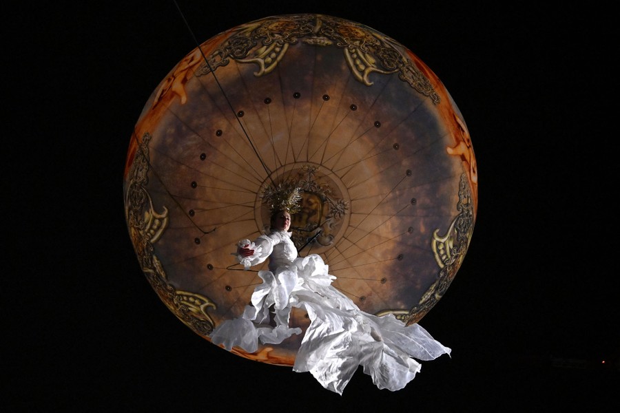 An acrobat performs hanging in the air above the photographer.