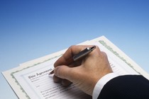 A man wearing a suit signs a contract