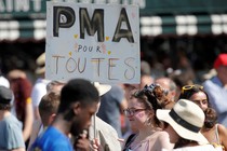 A participant in the Paris gay pride parade holds up a placard which reads "PMA (Fertility treatment) for all."