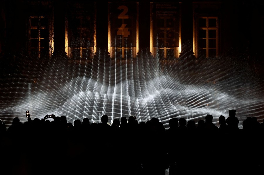 People take photos of a wavy-looking grid of light.