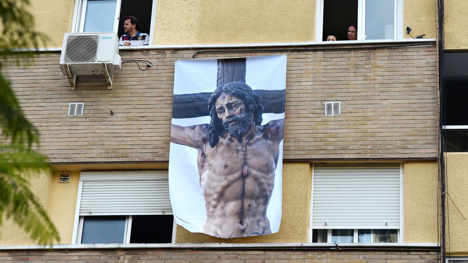 A poster depicting a religious image of Jesus Christ hangs on a facade on April 8, 2020, in Seville, where Easter processions were cancelled during a national lockdown to prevent the spread of the COVID-16 disease.