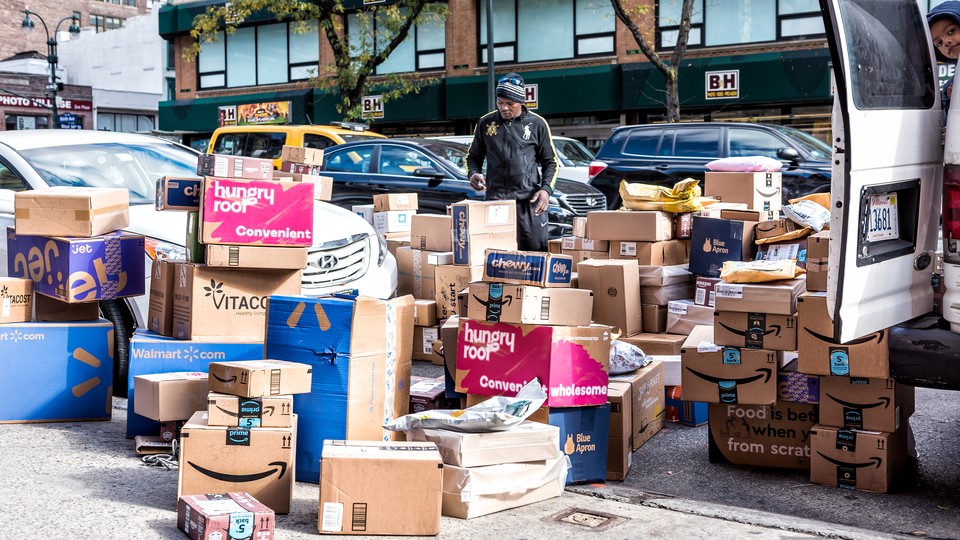 A deliveryman stands in a sea of subscription-service boxes on a sidewalk in NYC.