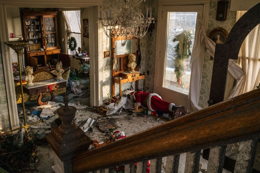 The interior of a home, with debris and decorations strewn about after a storm blew out windows.