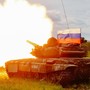 A Russian T-72 tank testfires with a Russian flag atop it.