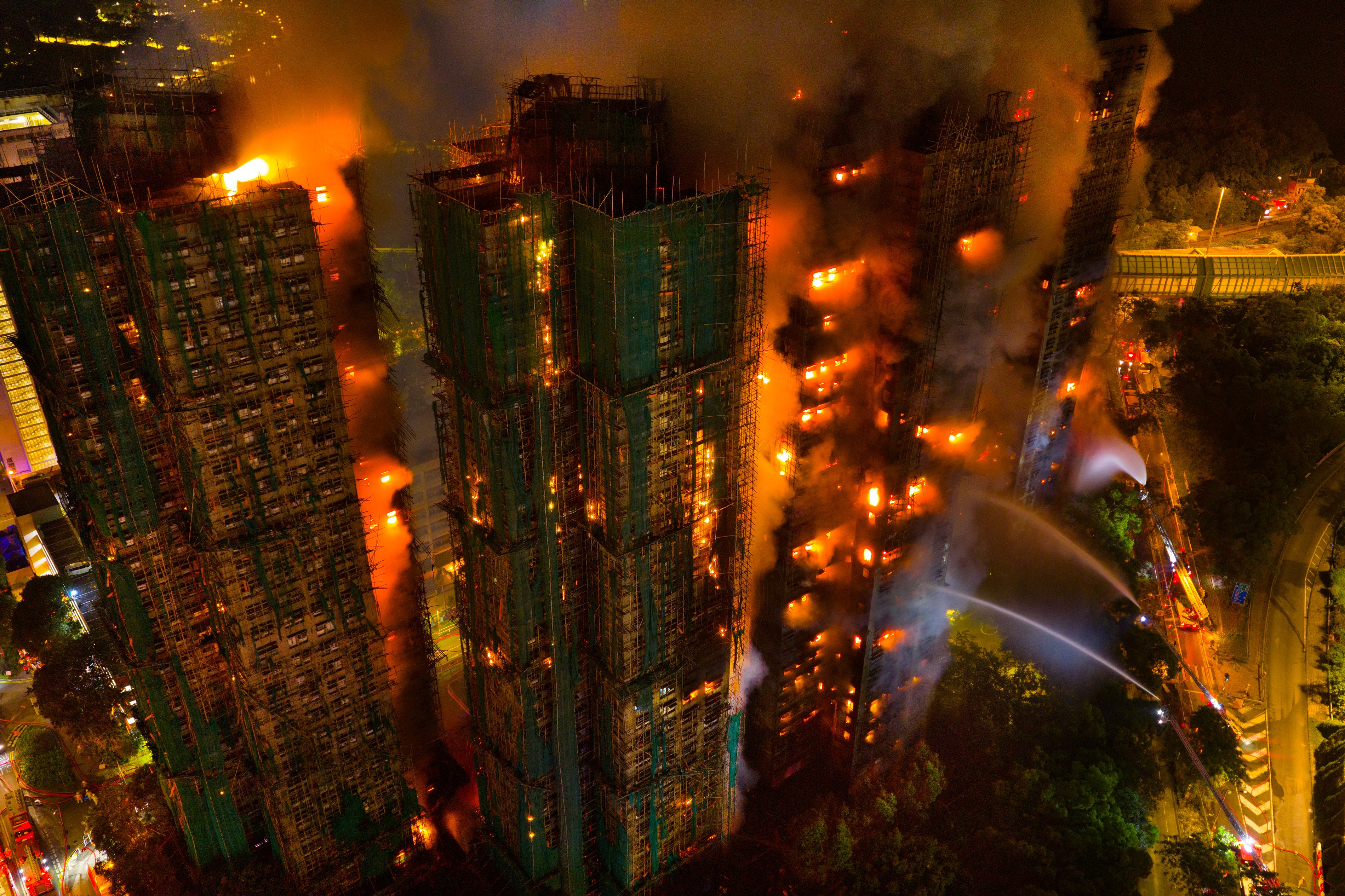 A drone view of a fire raging through tall apartment buildings