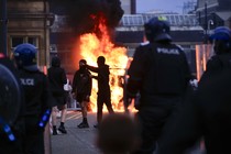 Rioters face off with police in front of a burning car in Sunderland, United Kingdom