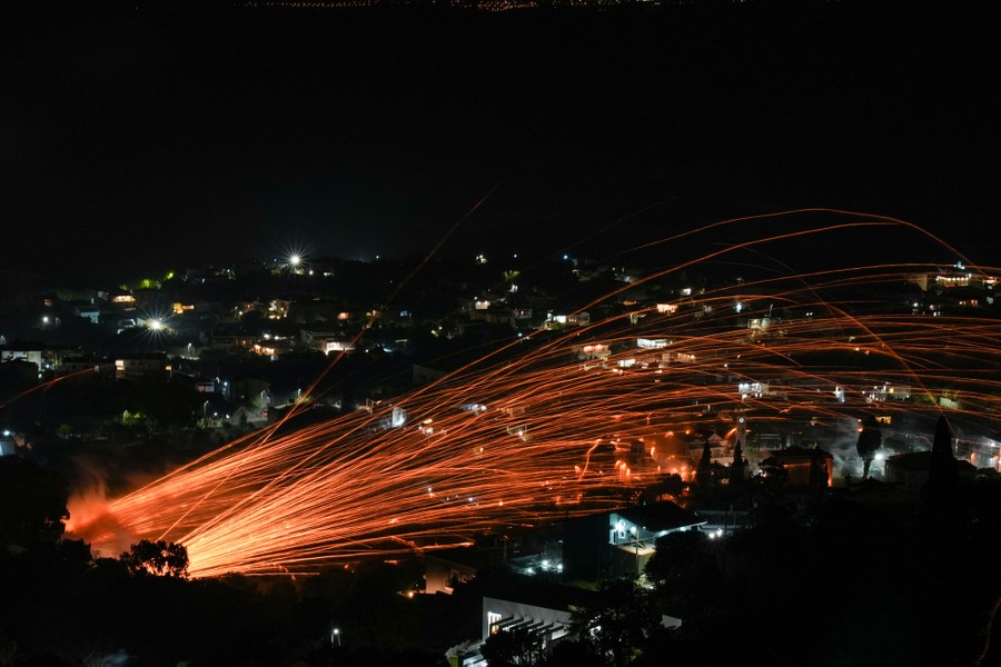 Small rockets leave many streaks of light, blasting from an unseen church at lower left, toward a rival church at right.