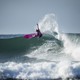 a photo of surfer in pink at the crest of a wave