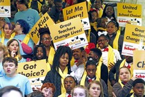 People hold signs reading "Let me learn," "United for school choice," and "Great teachers change lives."