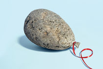 A photo realistic illustration of a balloon shaped rock with a red ribbon attached.