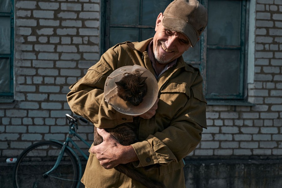 A person holds their cat that is wearing a plastic cone around its neck.