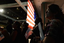 U.S.-citizenship candidates look at a video presentation as they wait to take the oath of citizenship at a naturalization ceremony.