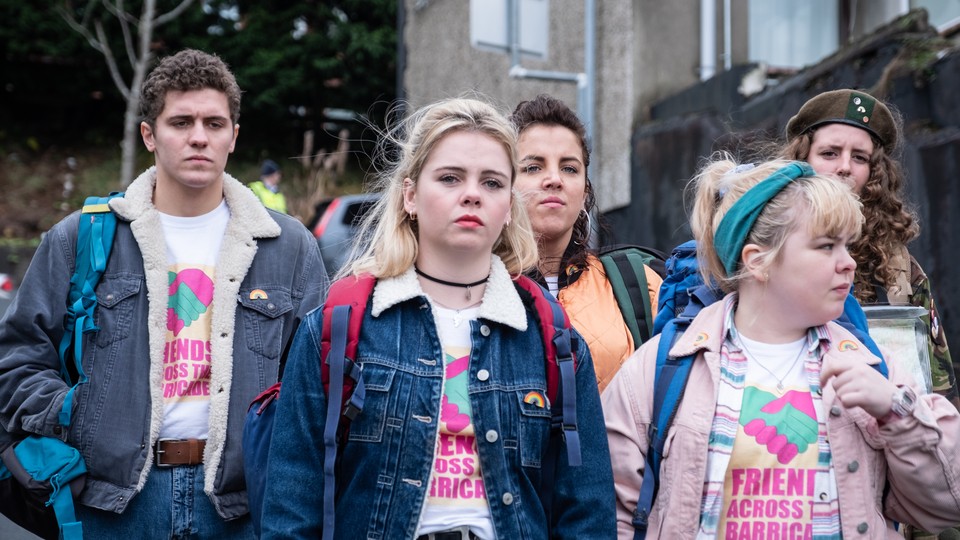 The five main characters in "Derry Girls" walking somberly down a neighborhood street