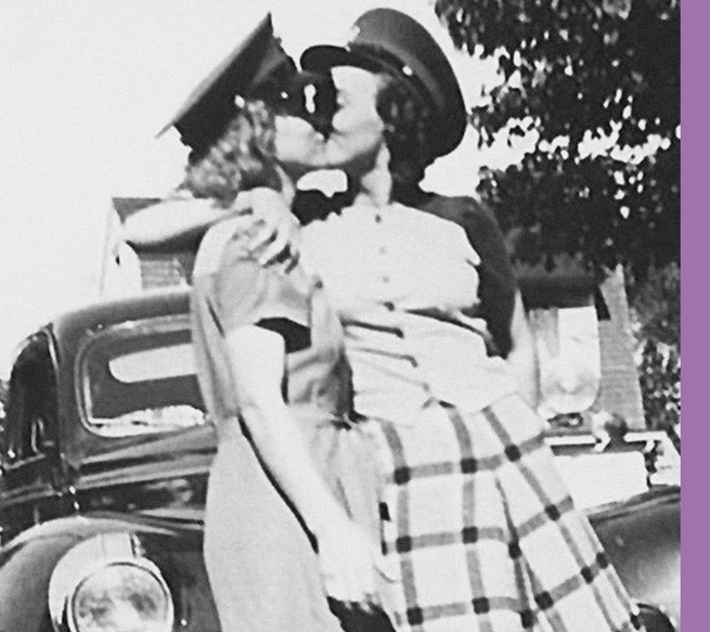 Black and White image of two women kissing wearing military hats