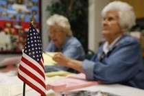 An American flag sits on the table where two Oklahoma poll workers are helping voters.