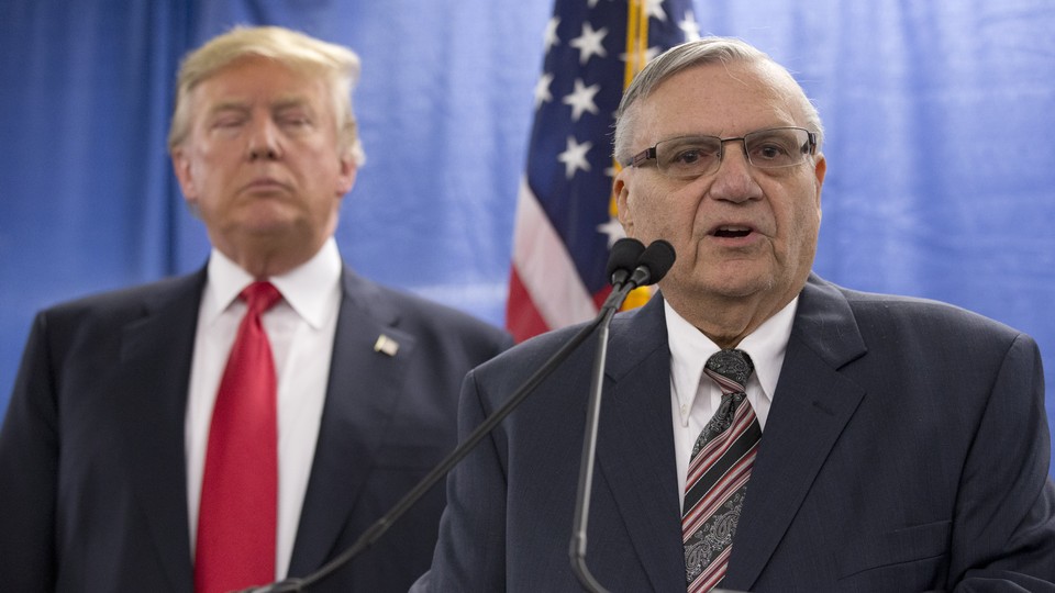 Joe Arpaio speaks with President Trump behind him.