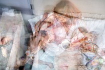 Photo illustration: multiple photographs of bed with mother and baby layered over one another