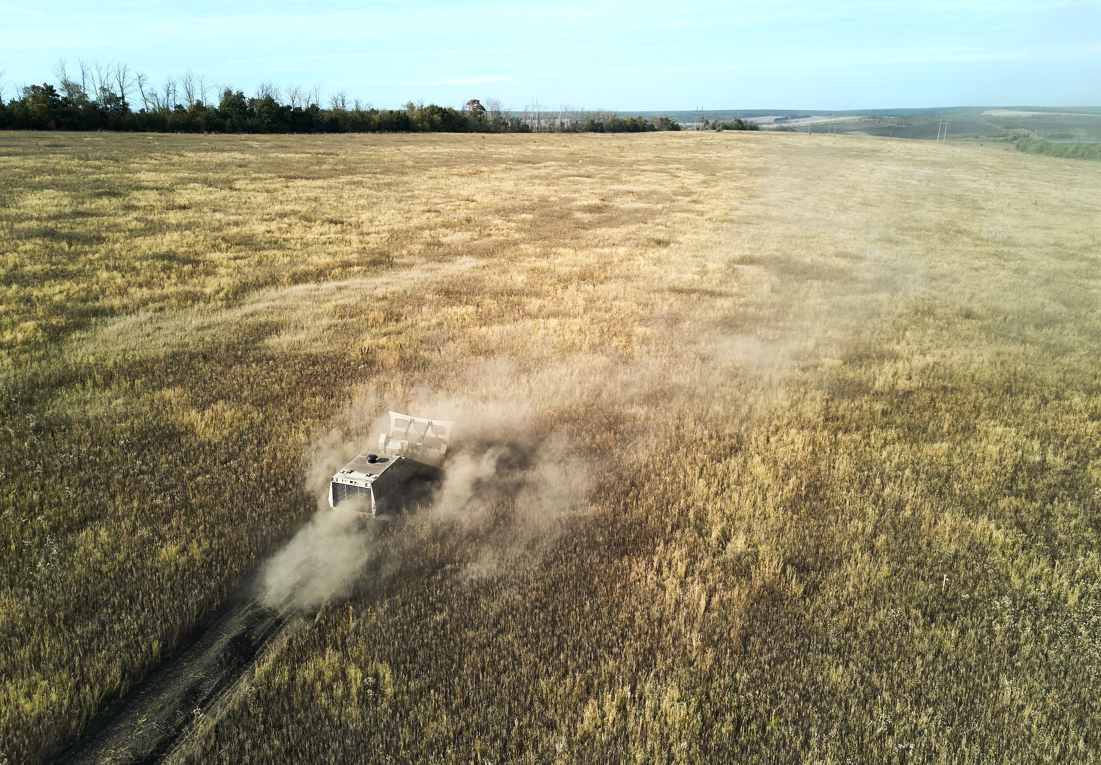 An aerial view of an unmanned vehicle crossing a farm field, clearing mines