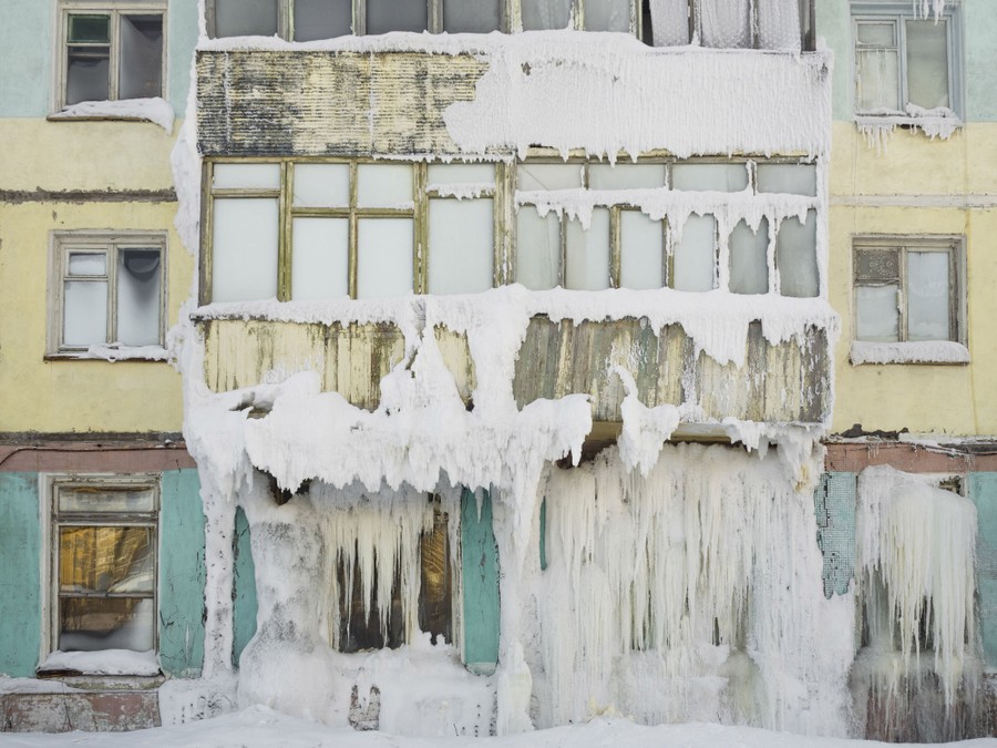 Large chunks of ice hang from the facade of an abandoned building.