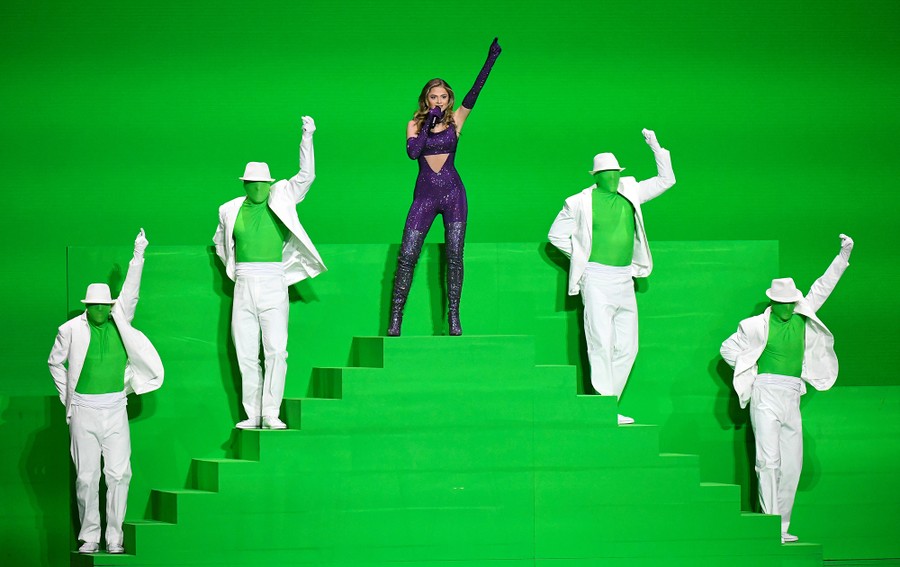 Performers pose on a green-screen stage.