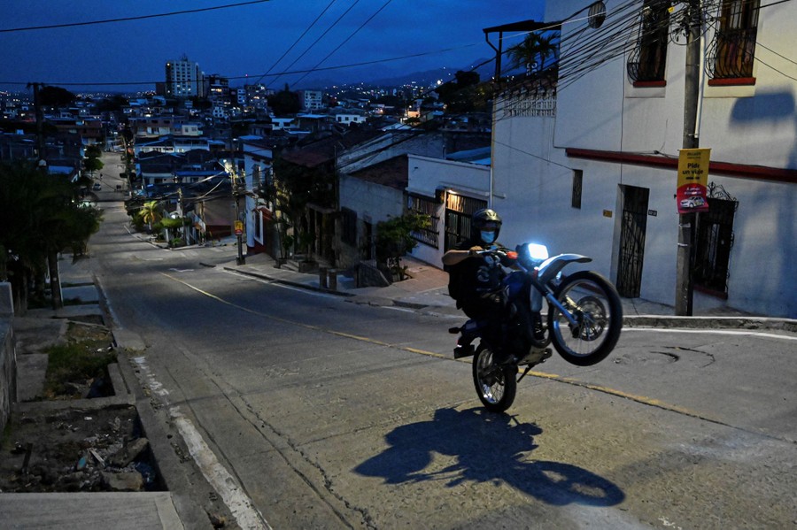 A man rides a motorcycle on an empty city street at night.