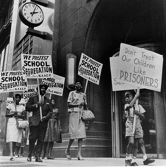 A black and white photo of Black Americans protesting school segregation.