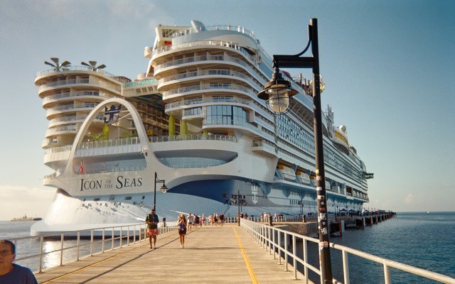 photo of Icon of the Seas, taken on a long railed path approaching the stern of the ship, with people walking along dock