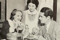 A man and woman eat dinner with their maid.