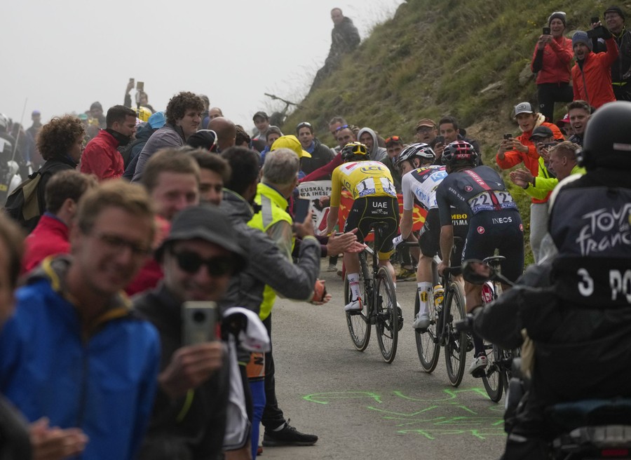 Cyclists climb a mountain pass surrounded by fans.