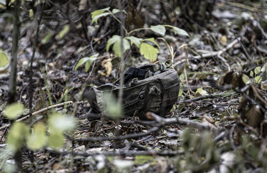 A soldier's helmet lies on the ground in a wood.