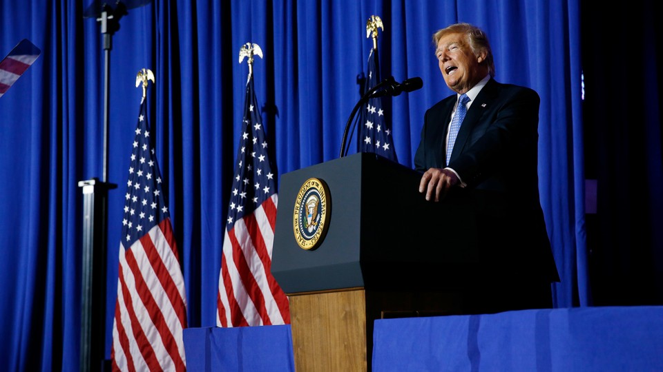 President Donald Trump delivers a speech in front of U.S. flags.