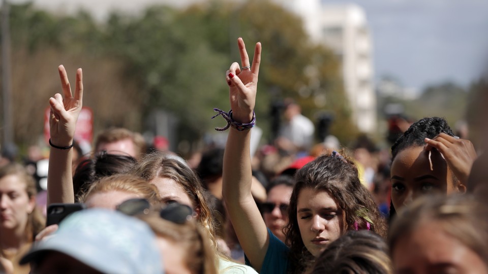 People raise their hands in peace signs at a rally.